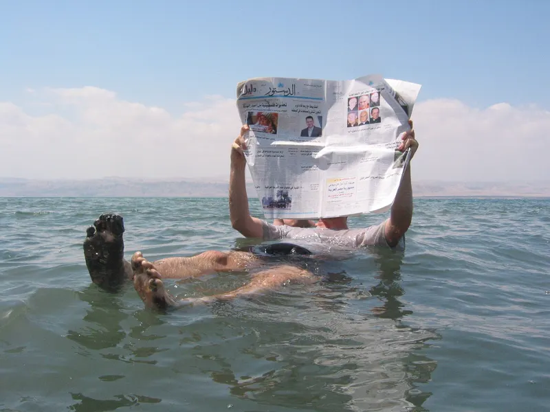 A man floating on the Dead Sea and reading a newspaper